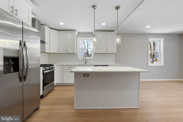 kitchen with tasteful backsplash, sink, white cabinets, a center island, and stainless steel appliances