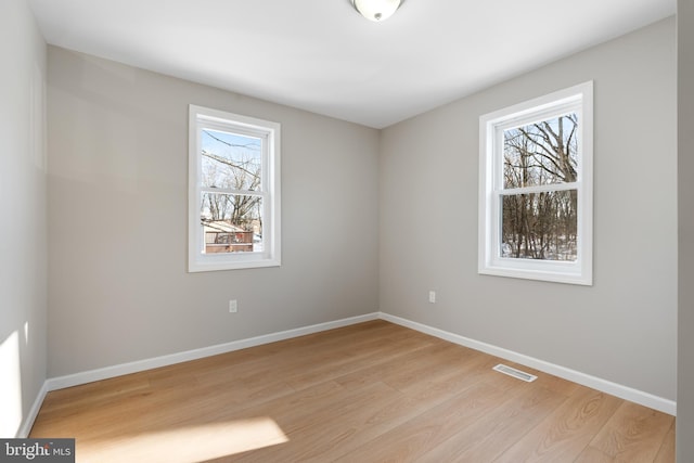 empty room with light hardwood / wood-style floors and a healthy amount of sunlight