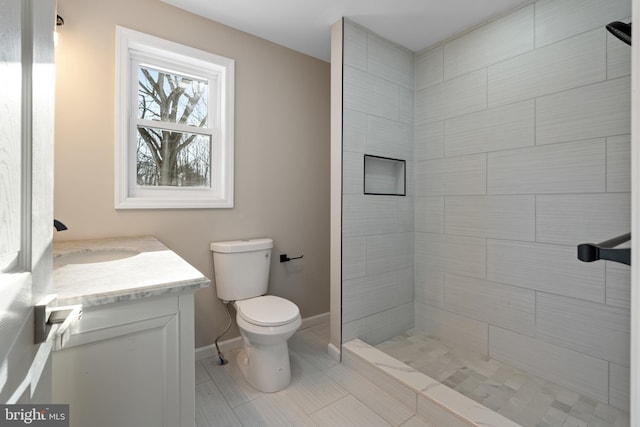 bathroom with vanity, toilet, and a tile shower