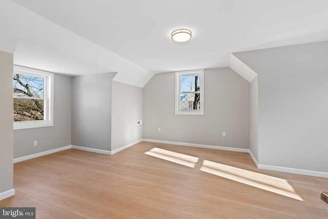 additional living space with vaulted ceiling, a wealth of natural light, and light hardwood / wood-style floors