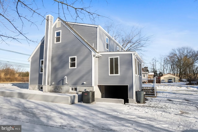 snow covered property with a garage and central AC unit