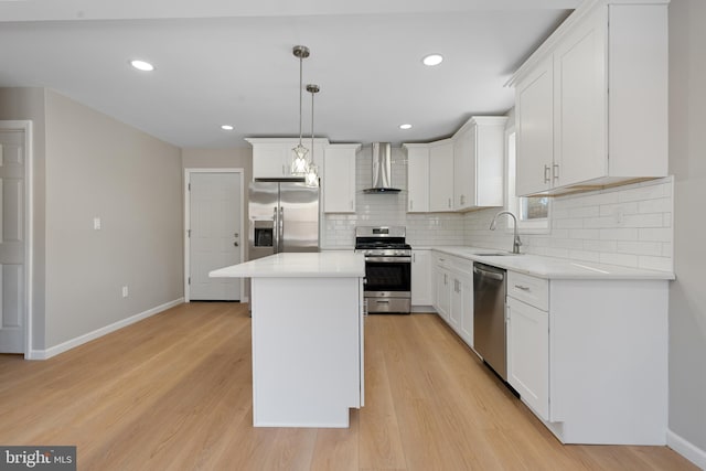 kitchen featuring white cabinetry, a center island, wall chimney exhaust hood, and appliances with stainless steel finishes