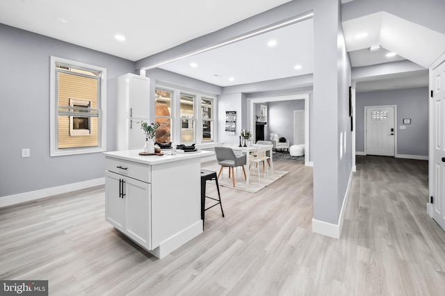 kitchen featuring a center island, white cabinets, a kitchen bar, and light hardwood / wood-style floors