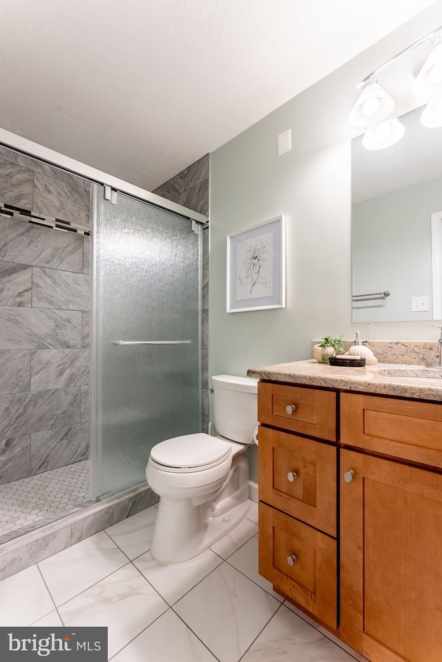 bathroom with a shower stall, vanity, toilet, and marble finish floor