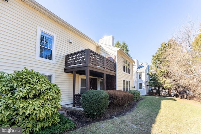 view of side of property featuring a balcony and a yard