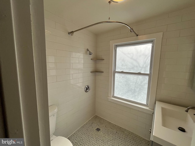 bathroom with sink, a wealth of natural light, toilet, and tiled shower