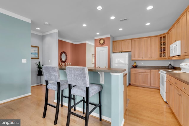 kitchen with crown molding, white appliances, a center island, light hardwood / wood-style floors, and light brown cabinets