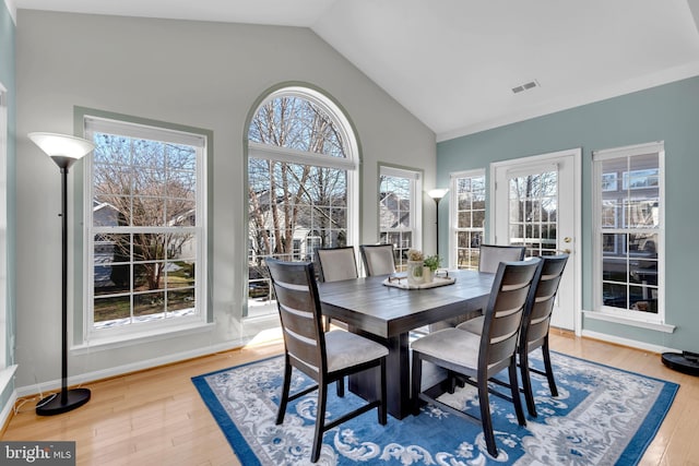 dining space featuring wood-type flooring and vaulted ceiling