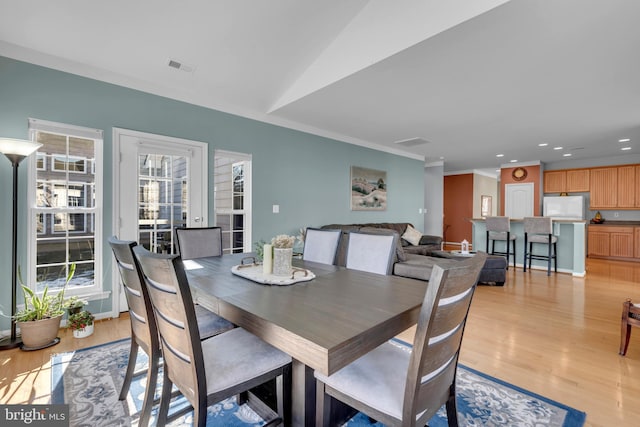 dining space with lofted ceiling and light hardwood / wood-style flooring