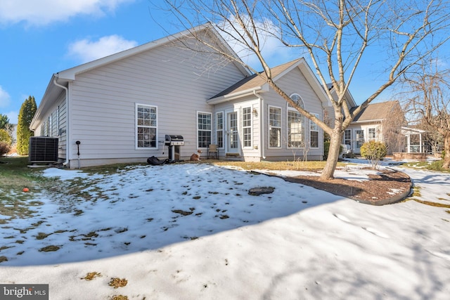 snow covered rear of property featuring central air condition unit