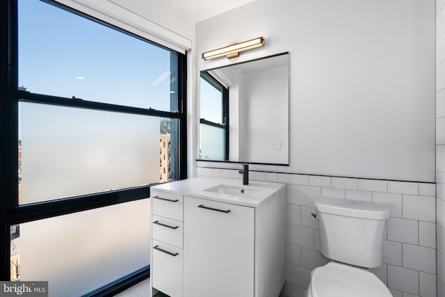 bathroom with vanity, tile walls, and toilet