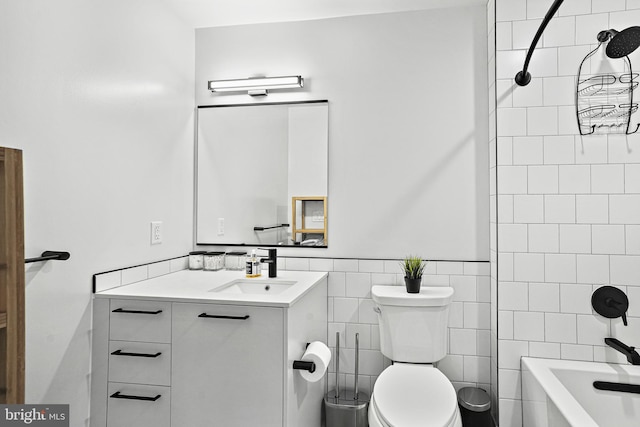 full bathroom featuring vanity, toilet, tiled shower / bath combo, and tile walls