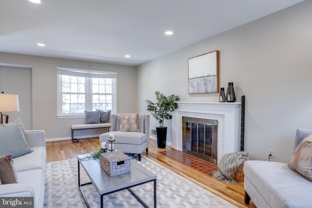 living area with a fireplace with flush hearth, baseboards, recessed lighting, and wood finished floors