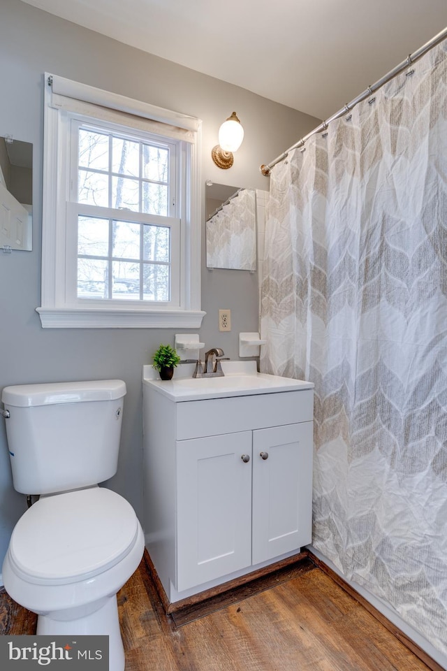 full bath with toilet, wood finished floors, and vanity