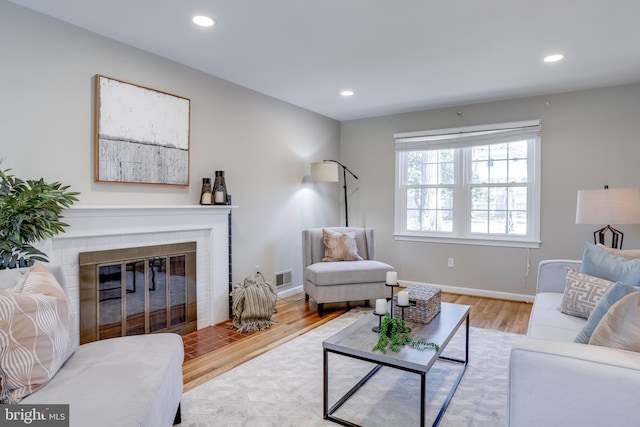 living room with recessed lighting, visible vents, and wood finished floors