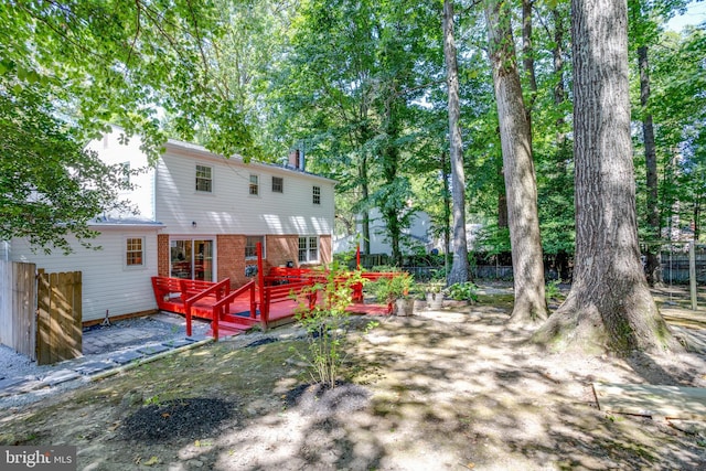 back of property featuring brick siding, a wooden deck, and fence