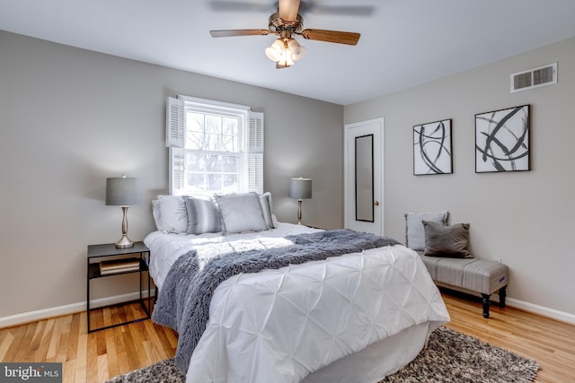 bedroom featuring ceiling fan, baseboards, visible vents, and wood finished floors
