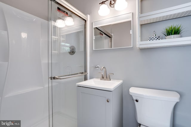 bathroom featuring toilet, a shower stall, and vanity