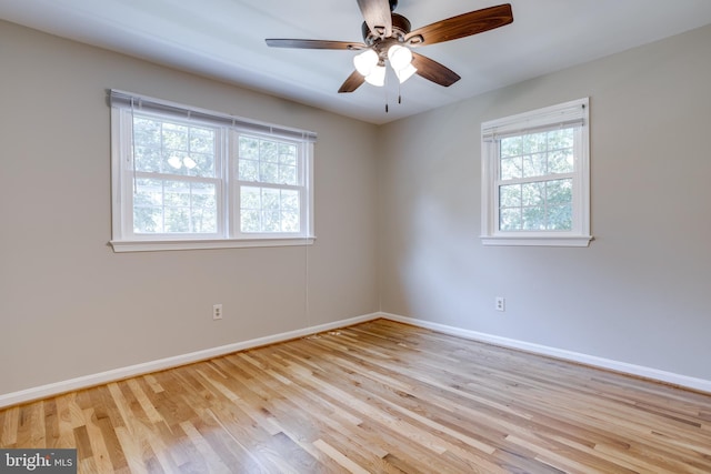 unfurnished room featuring baseboards, wood finished floors, and a wealth of natural light