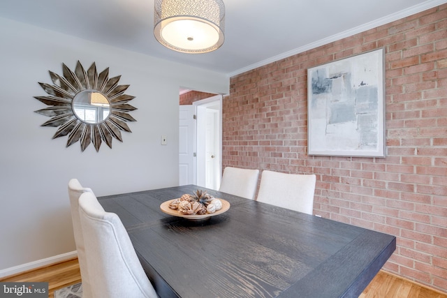 dining room featuring brick wall and wood finished floors