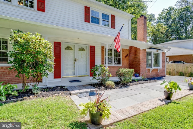 view of front of home with fence, covered porch, a chimney, and brick siding