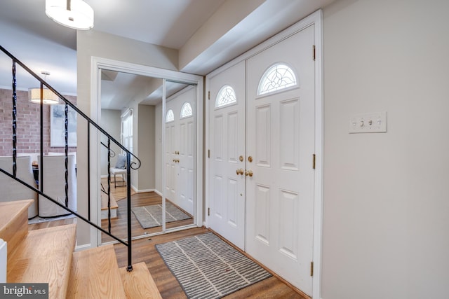 foyer entrance featuring baseboards, plenty of natural light, stairs, and wood finished floors