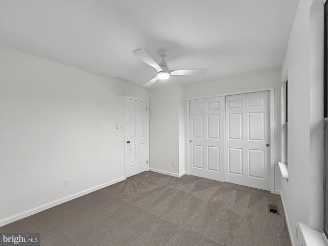 unfurnished bedroom with dark carpet, ceiling fan, and a closet