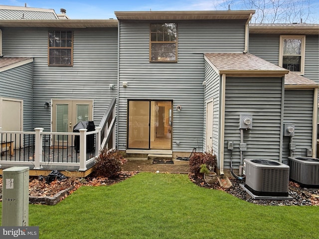 back of house featuring a lawn and central air condition unit