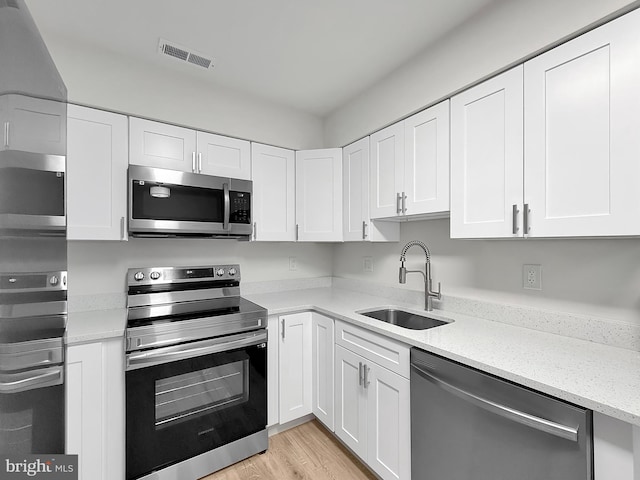 kitchen with sink, light hardwood / wood-style flooring, stainless steel appliances, and white cabinets