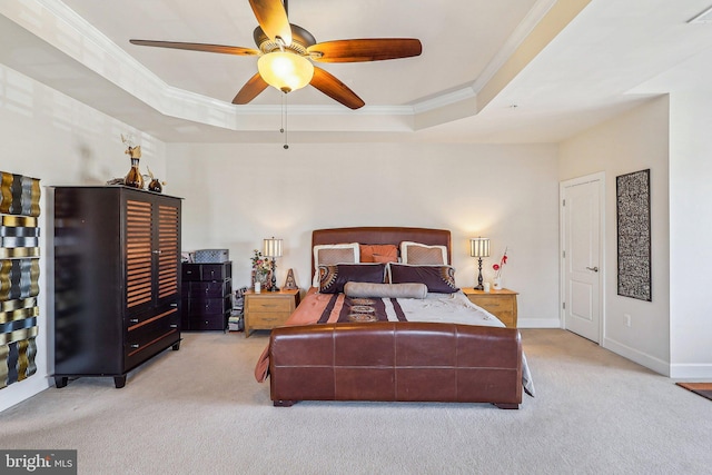 bedroom with ornamental molding, a tray ceiling, and light carpet