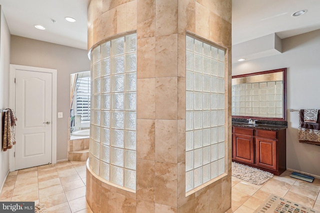 bathroom featuring tile patterned flooring, vanity, and tiled bath