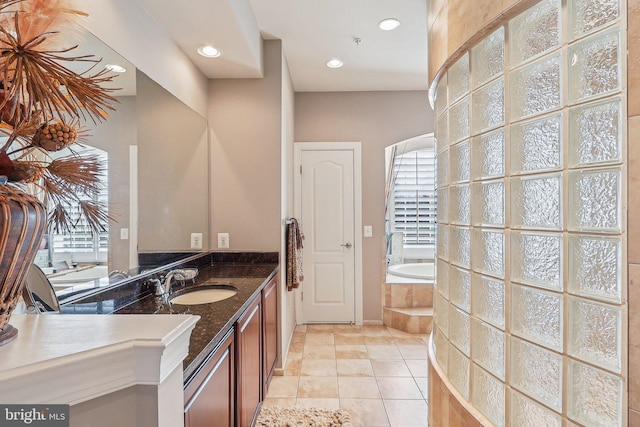 bathroom featuring tiled tub, vanity, and tile patterned floors