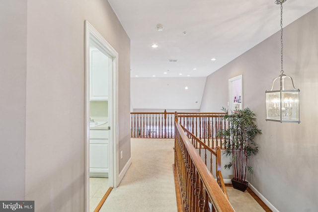 hall with a notable chandelier and light colored carpet