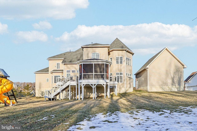 snow covered back of property featuring a wooden deck, a sunroom, and a lawn