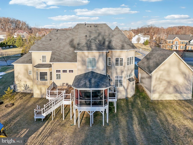 rear view of house featuring a yard, a deck, and a sunroom