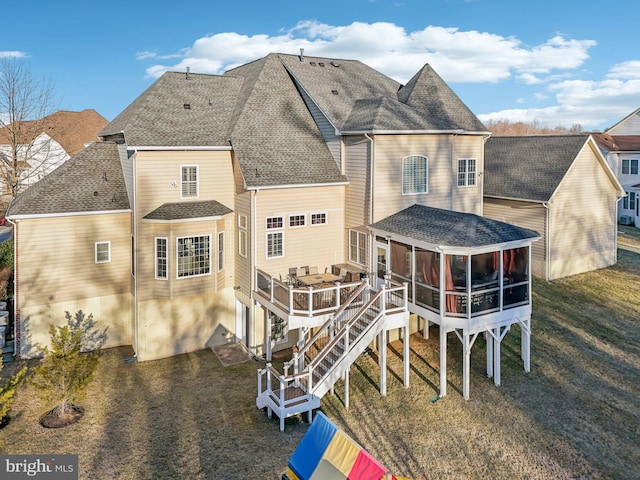 back of property with a lawn, a sunroom, and a deck