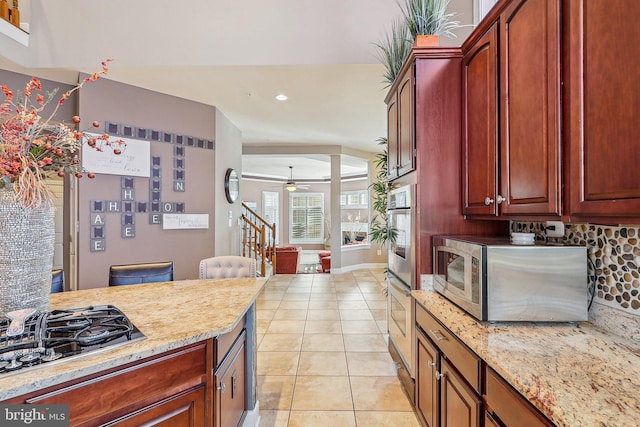 kitchen featuring light tile patterned floors, ceiling fan, backsplash, stainless steel appliances, and light stone countertops