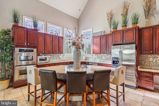 kitchen with stainless steel appliances, tasteful backsplash, light stone counters, and a kitchen breakfast bar