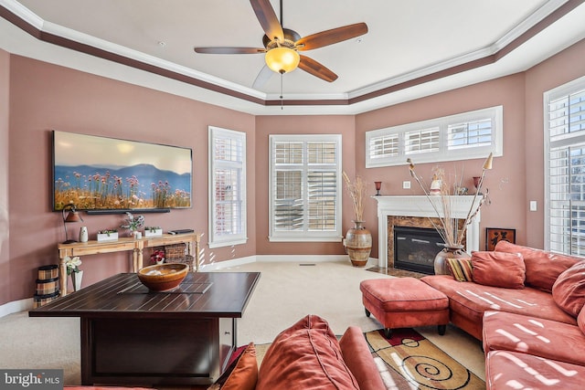 living room with carpet floors, ornamental molding, ceiling fan, a raised ceiling, and a premium fireplace