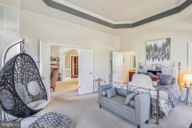 carpeted bedroom with ornamental molding, connected bathroom, a raised ceiling, and a high ceiling