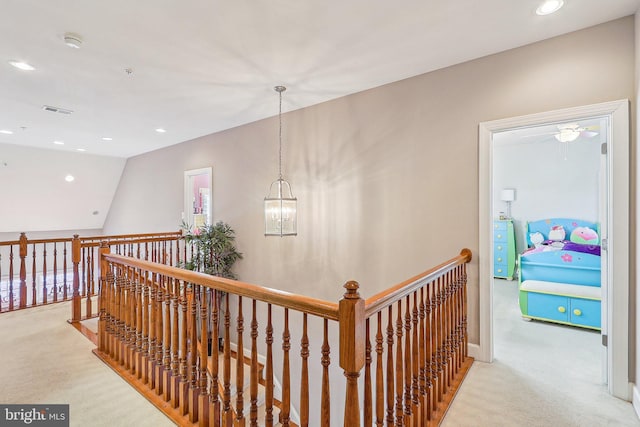 corridor with light colored carpet, lofted ceiling, and a chandelier