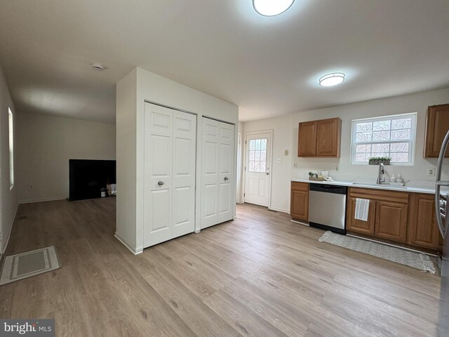 kitchen featuring light wood finished floors, visible vents, light countertops, stainless steel dishwasher, and a sink