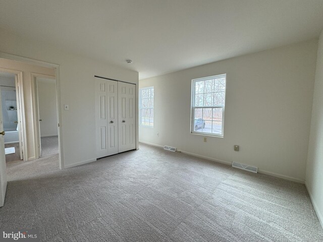 unfurnished bedroom featuring a closet, carpet flooring, visible vents, and baseboards