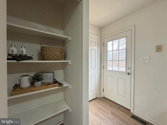 doorway to outside featuring baseboards, visible vents, and wood finished floors