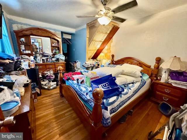 bedroom with wood-type flooring, a textured ceiling, and ceiling fan