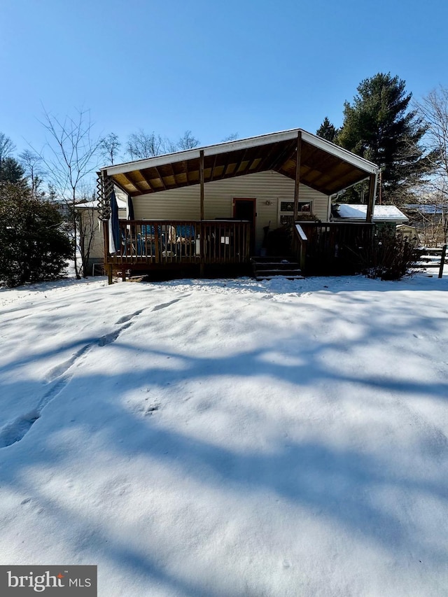 snow covered back of property featuring a deck