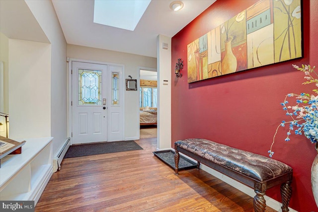 foyer entrance with hardwood / wood-style flooring, a baseboard radiator, and a skylight