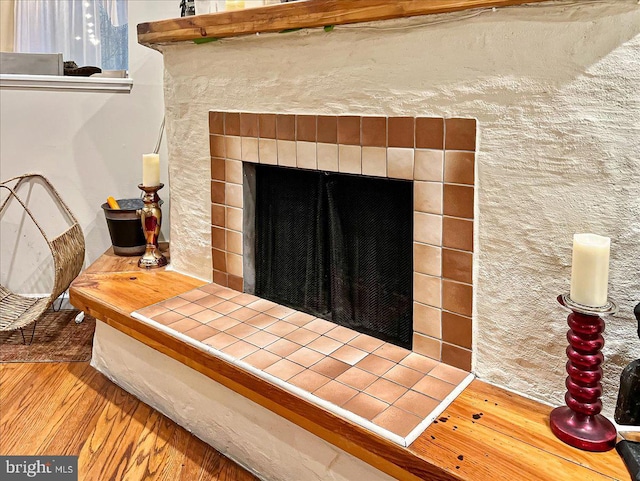 interior details with a tiled fireplace and hardwood / wood-style floors