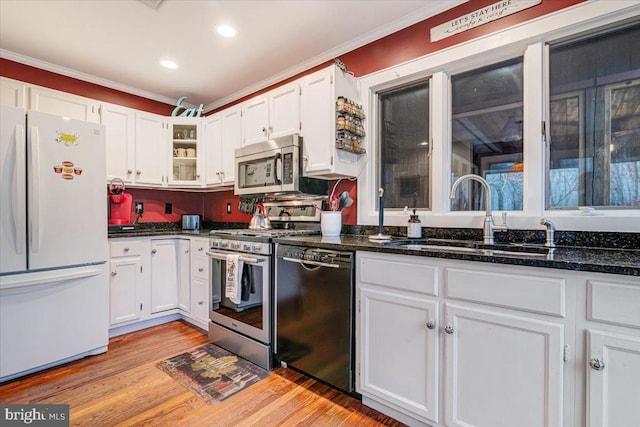 kitchen with stainless steel appliances, white cabinets, dark stone counters, and light hardwood / wood-style flooring