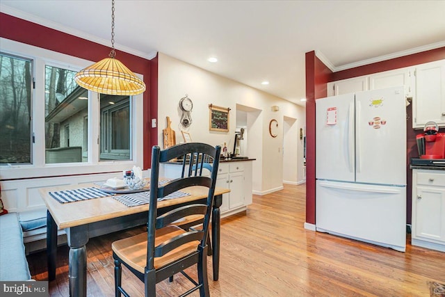 dining space featuring ornamental molding and light hardwood / wood-style floors